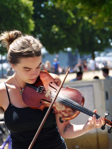 Young woman playing a viola in the sunshine at Saturday Market.