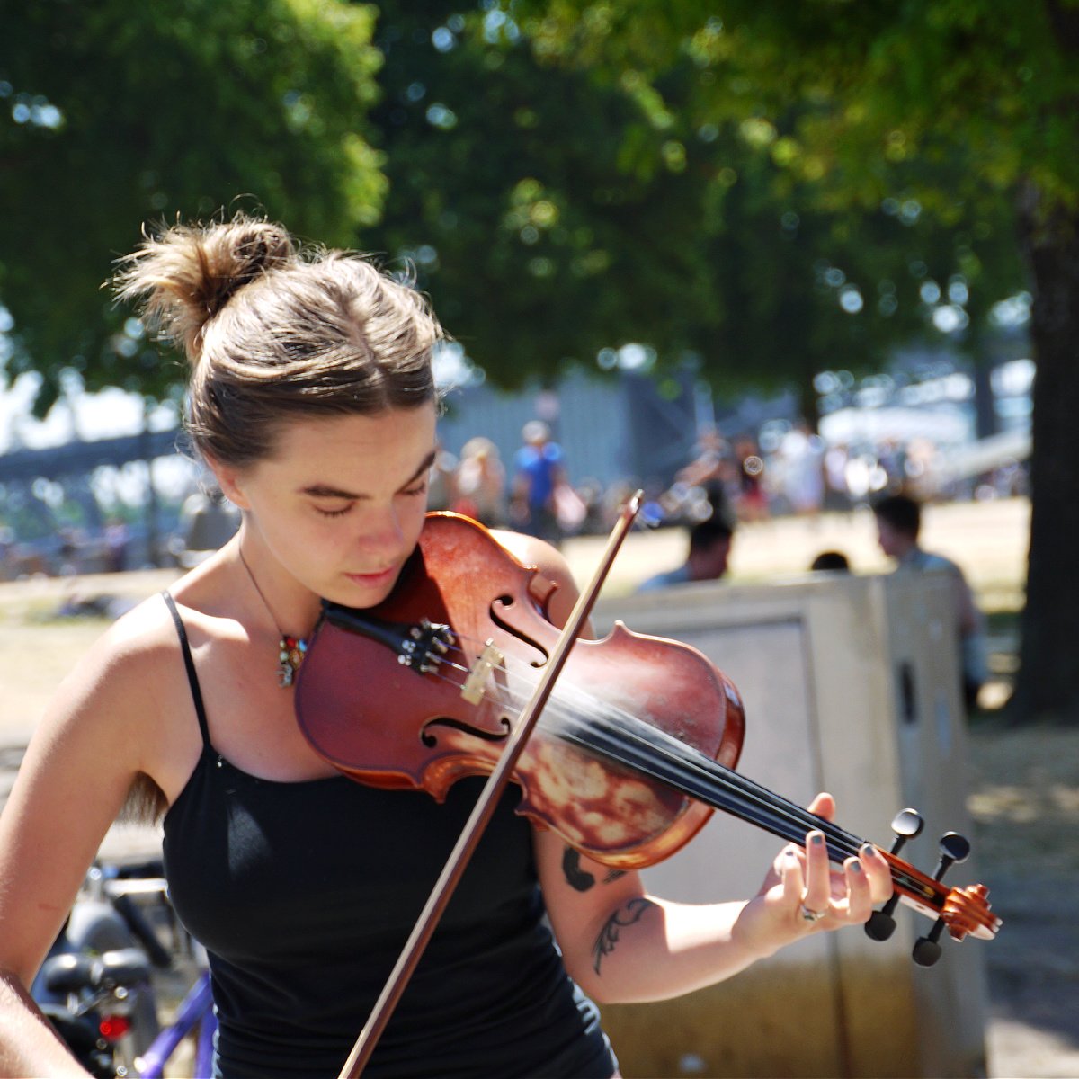 Young woman playing a viola in the sunshine at Saturday Market.