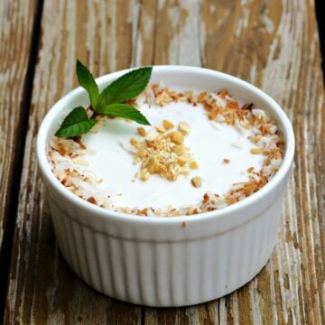 Vietnamese Banana Tapioca Pudding (Chè Chuối) in a small ramekin on an old wooden bench.