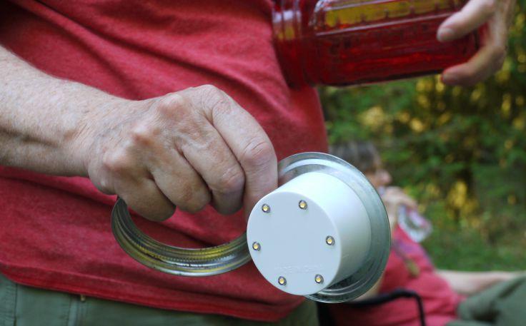 Older hand displaying the underside of a Mason Jar LED insert. 