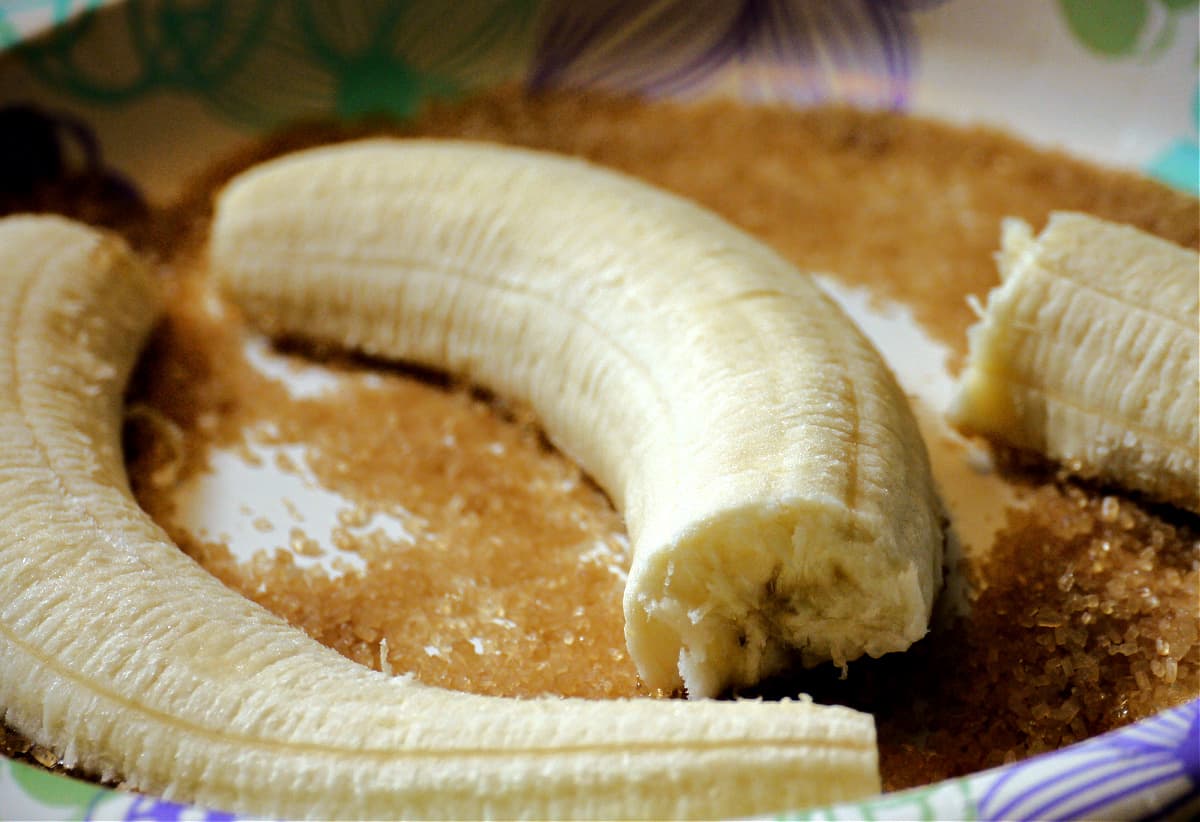 Cut bananas on parchment with raw sugar.