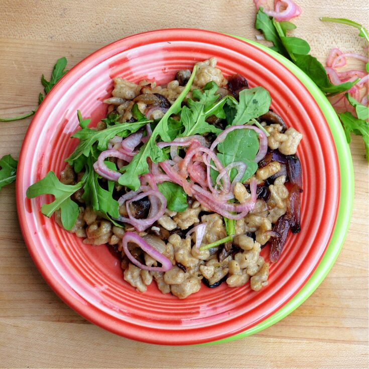 Overhead shot of Sourdough Spaetzle plated with caramelized cipollini, sauteed mushrooms, and tabasco shallots.