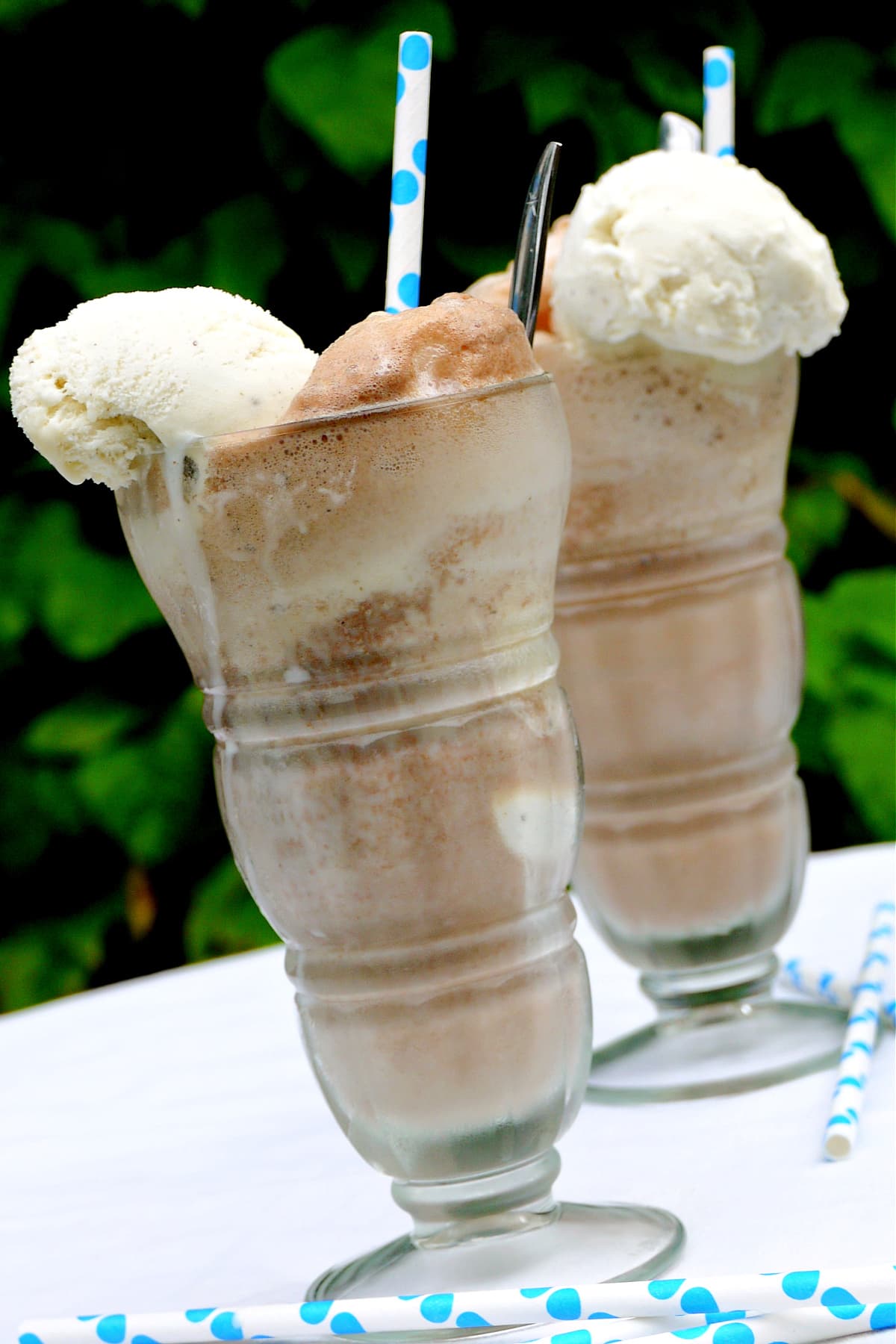 Close-up of two large, tall glasses filled with chocolate ice cream sodas.