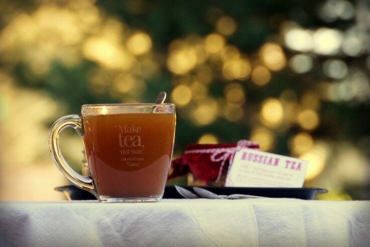 Russian Tea in a large, clear glass teacup. Sunlight dapples the background. 