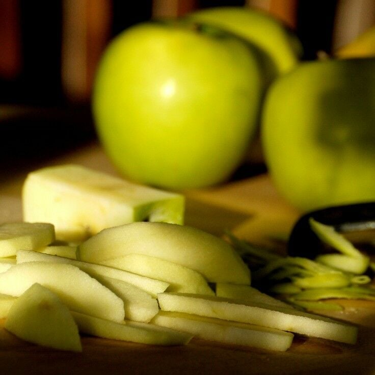 Granny Smith apples sliced and on a cutting board. 