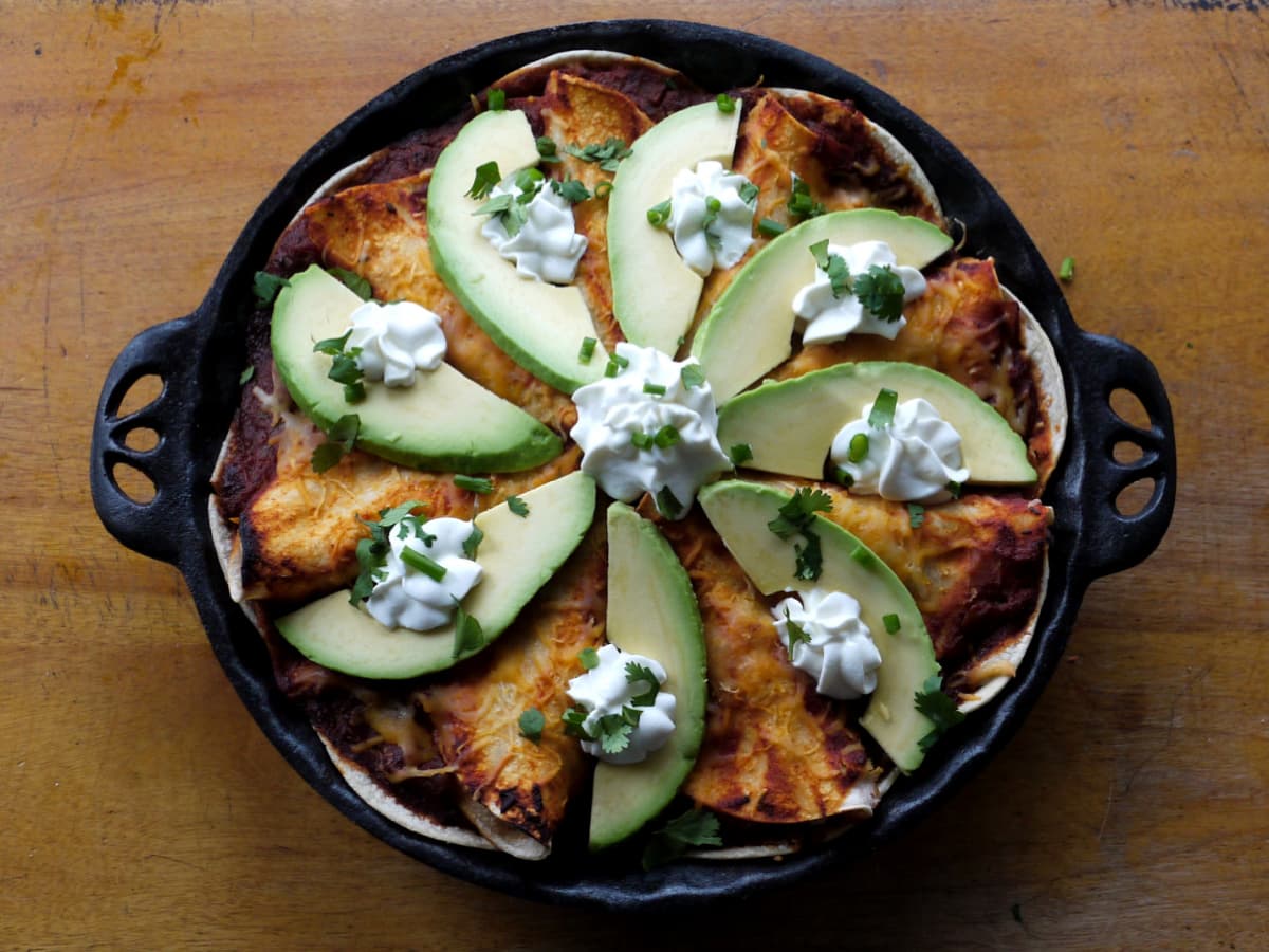 Baked enchilada pie is an easy enchilada casserole garnished with avocado slices, sour cream, and chopped cilantro.