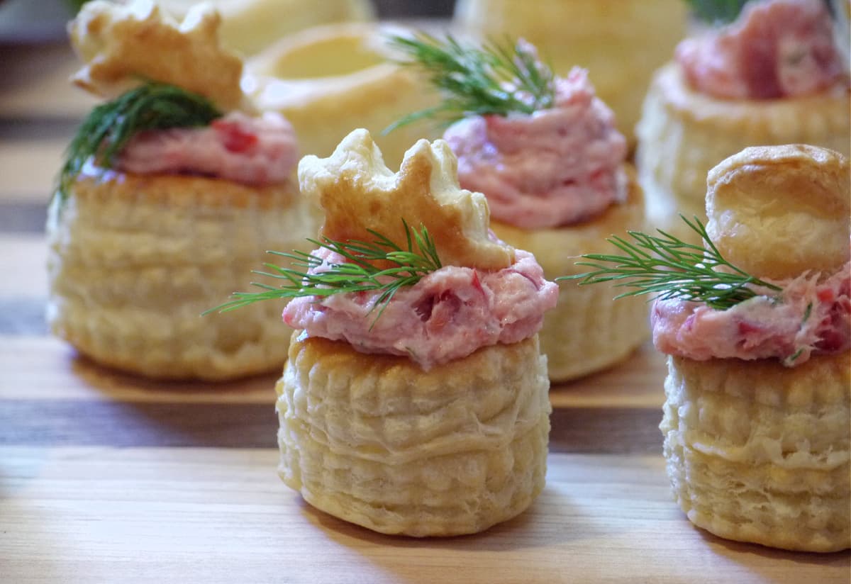 Close-up of Smoked Salmon Pastry Cup Appetizers on a cutting board, garnished and ready to serve.