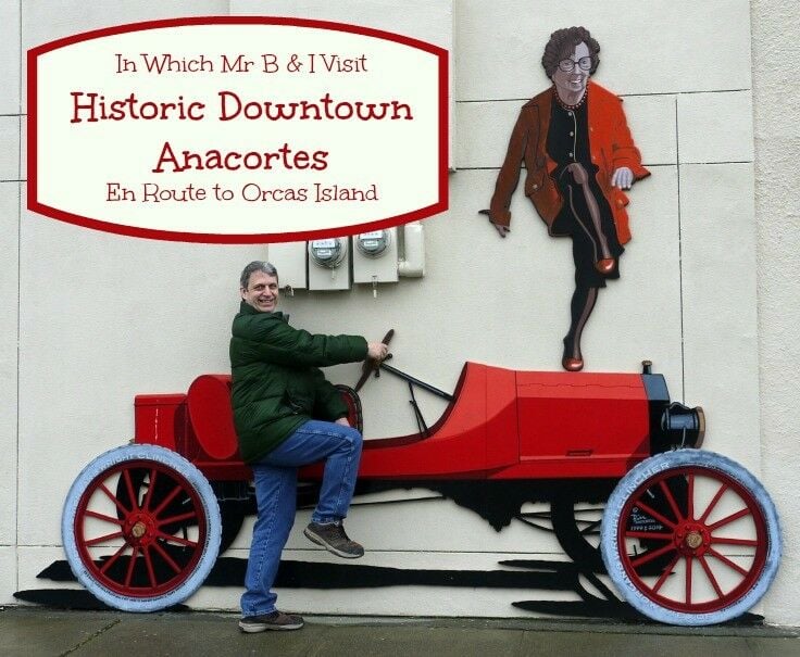 Middle-aged man pretending to board a 2-dimensional depiction of a bright red, convertible Model A. A middle aged woman with short dark hair is dancing on the car's hood.  