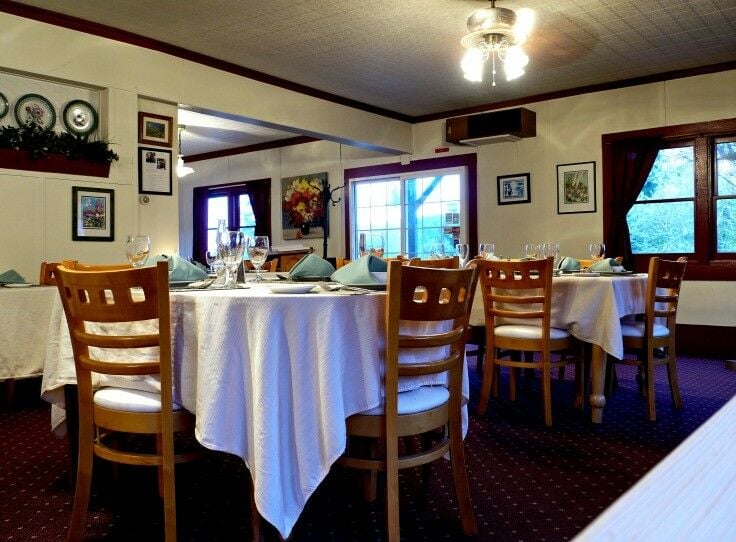 Deer Harbor Inn Restaurant dining area, with tables set with white linens table clothes and sage napkins.