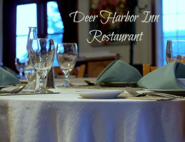 Shot of well-set dining table with water glasses, sage colored napkins, and white plates. 