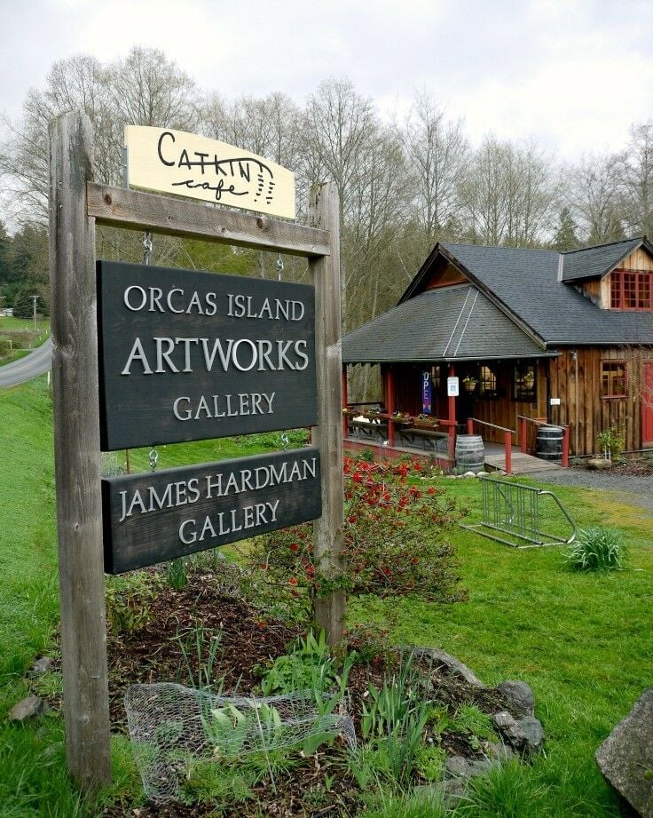 Wooden sign in front of Orcas Island Artworks & Catkin Cafe with cafe in the background. 