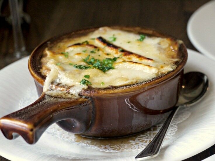 French onion soup in a traditional brown, handled soup bowl. 