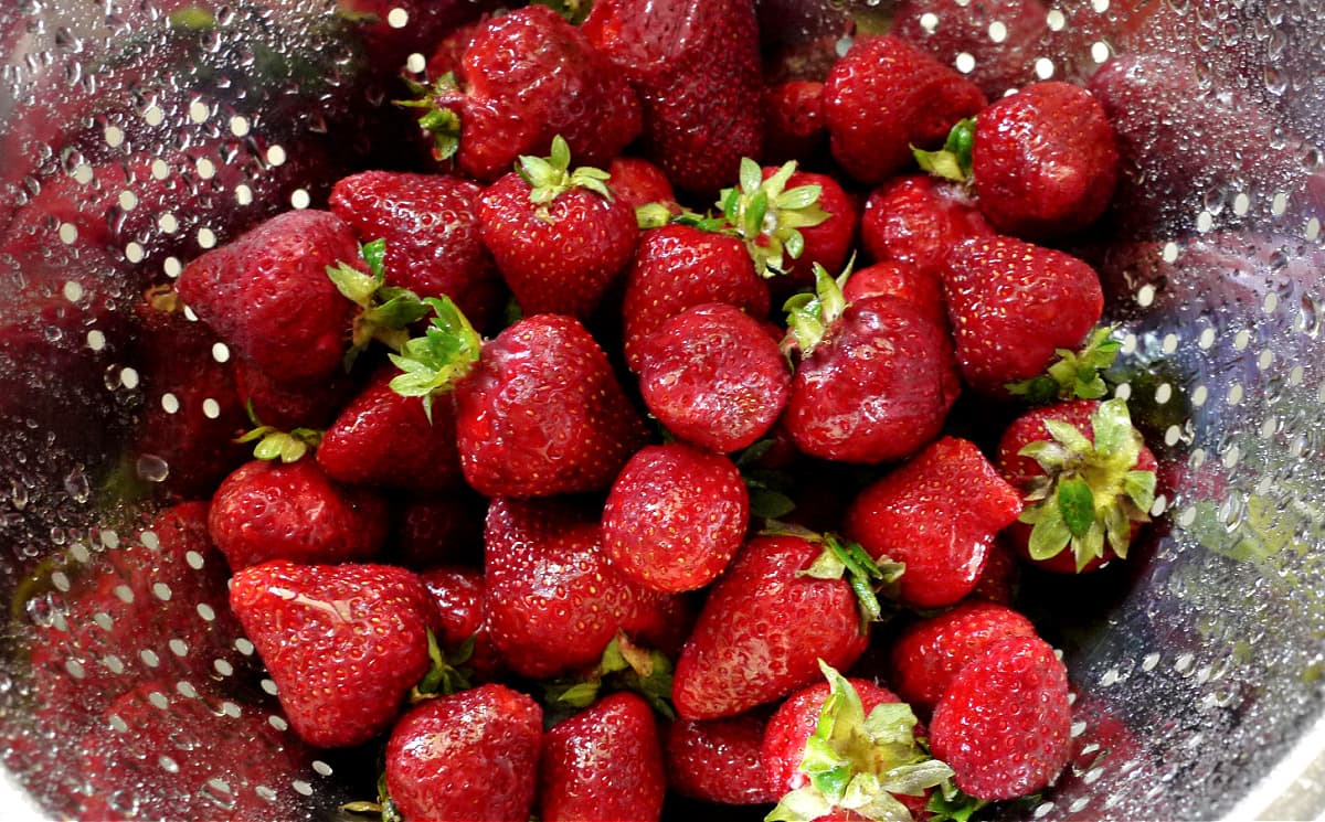 Colander filled with freshly rinsed strawberries.