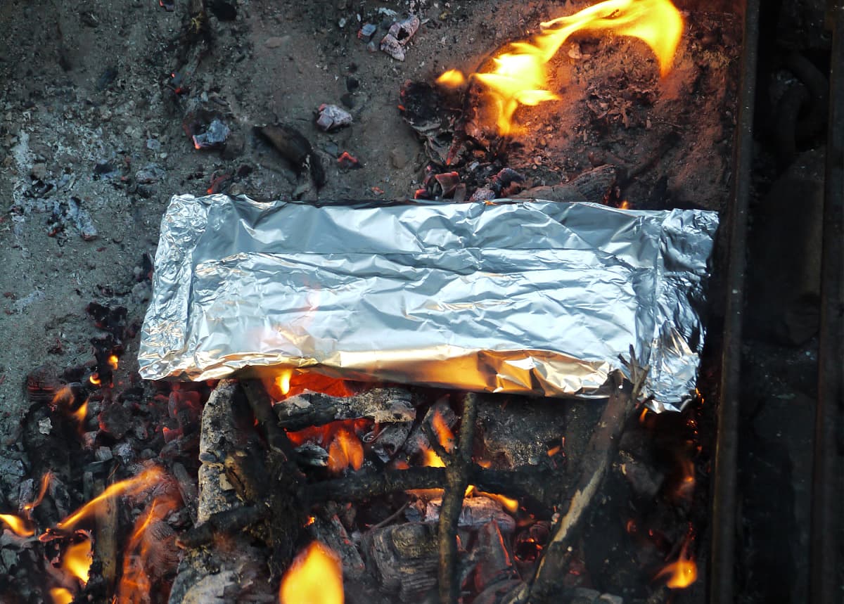 Wrapped foil dinner cooking on coals.