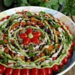 Family-sized salad bowl filled with greens, vegetables, quinoa, and roasted vegetables, dressed with sour cream and avocado dressings.