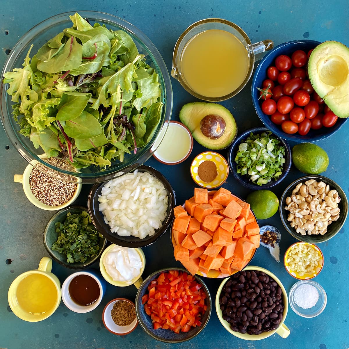 All Cuban Salad ingredients displayed in individual bowls  on blue table. 