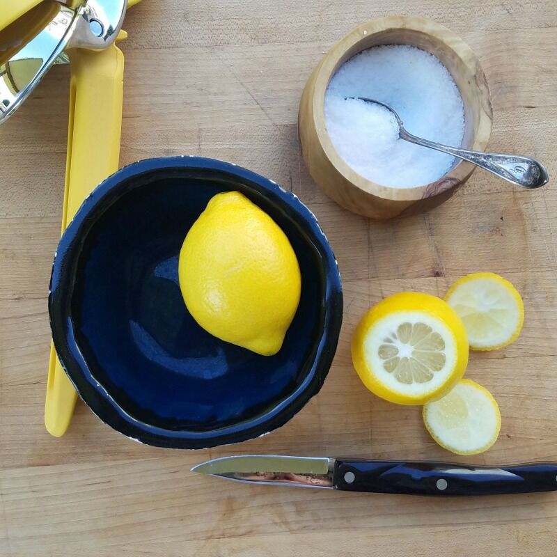 Lemon in a small bowl, knife, salt. 