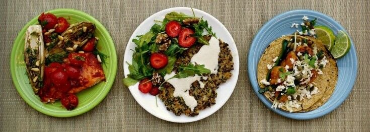 Three plates of food in a row on a bamboo mat. 