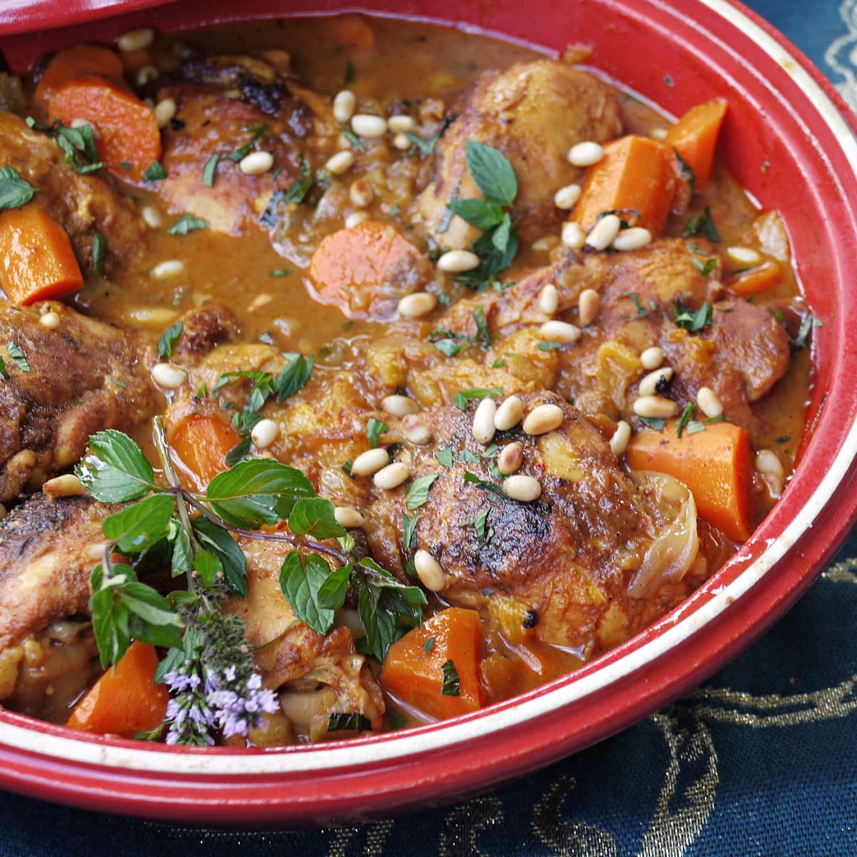 Closeup of Chicken tagine, garnished with fresh herbs and pine nuts. 