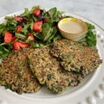 Three quinoa patties plated and served with a strawberry salad.