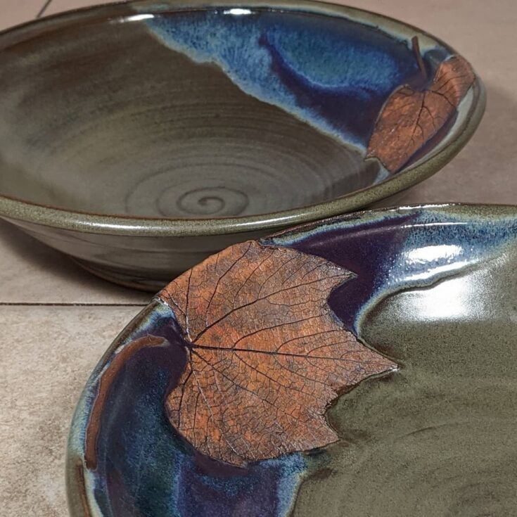 Side view of two clay pasta bowls, adorned with grape leaf emboss.