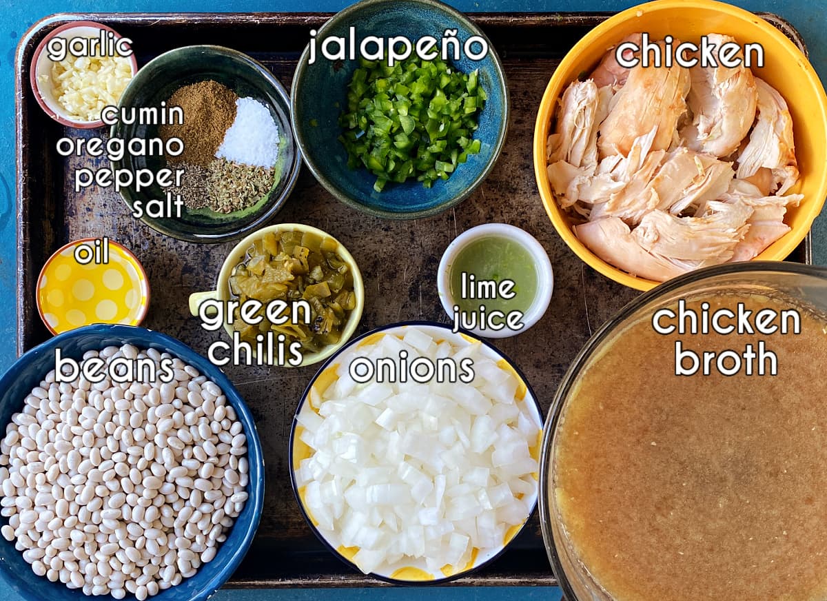 Chicken chili ingredients; labeled: jalapeños, chicken, chicken broth, onions, lime, beans, oil, garlic, spices.