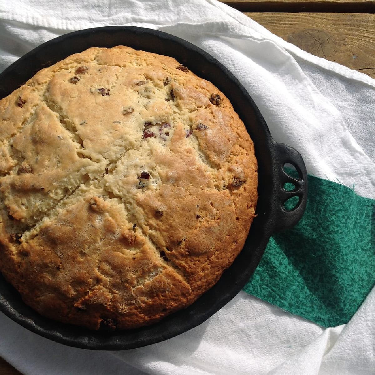 Round loaf of soda bread dotted with raisins, baked in a cast iron pie dish.