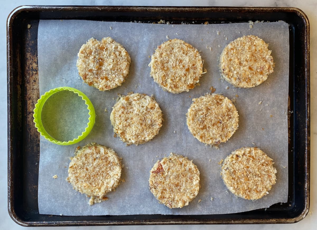 Crab cakes formed and resting on a parchment lined tray, ready to fry.