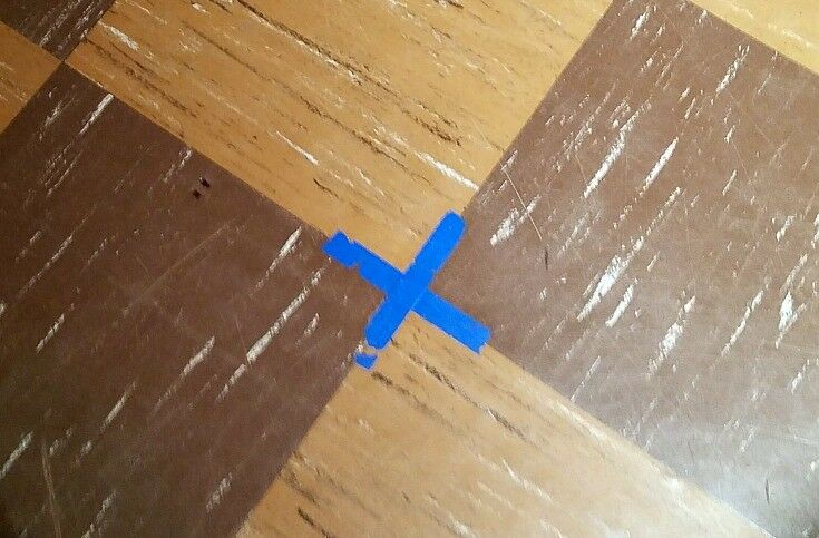 BBlue tape X on brown linoleum floor