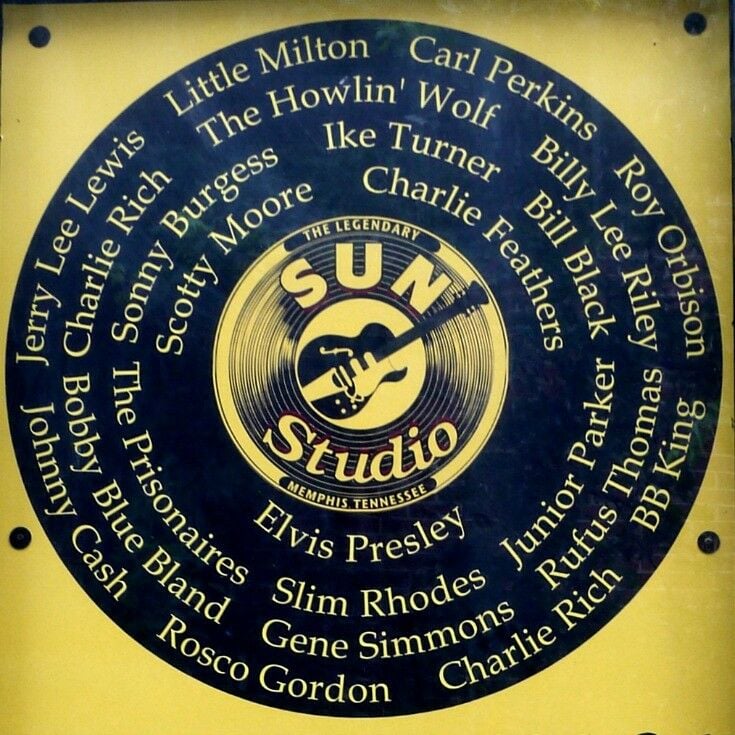 Round, black and yellow record-shaped sign with a guitar and Sun Records in the center, and recording artists' names where music grooves would be. 