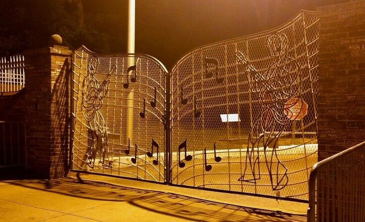 Gates of Graceland, with music notes and line-drawn, stylized Elvis playing guitar on either side. 