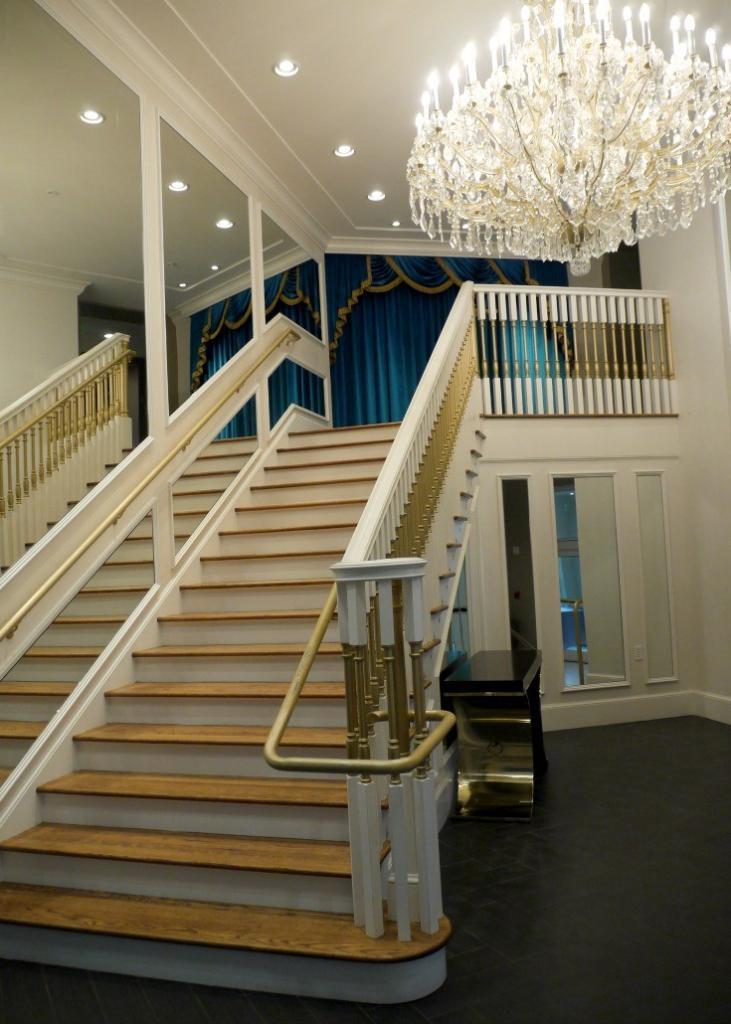 Grand Staircase at Graceland, complete with the blue curtain at the top of the stairs, the mirrored wall and the chandelier