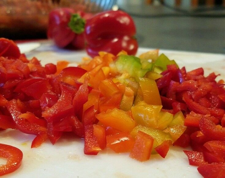 Extreme close-up of chopped red, yellow, and orange peppers. 