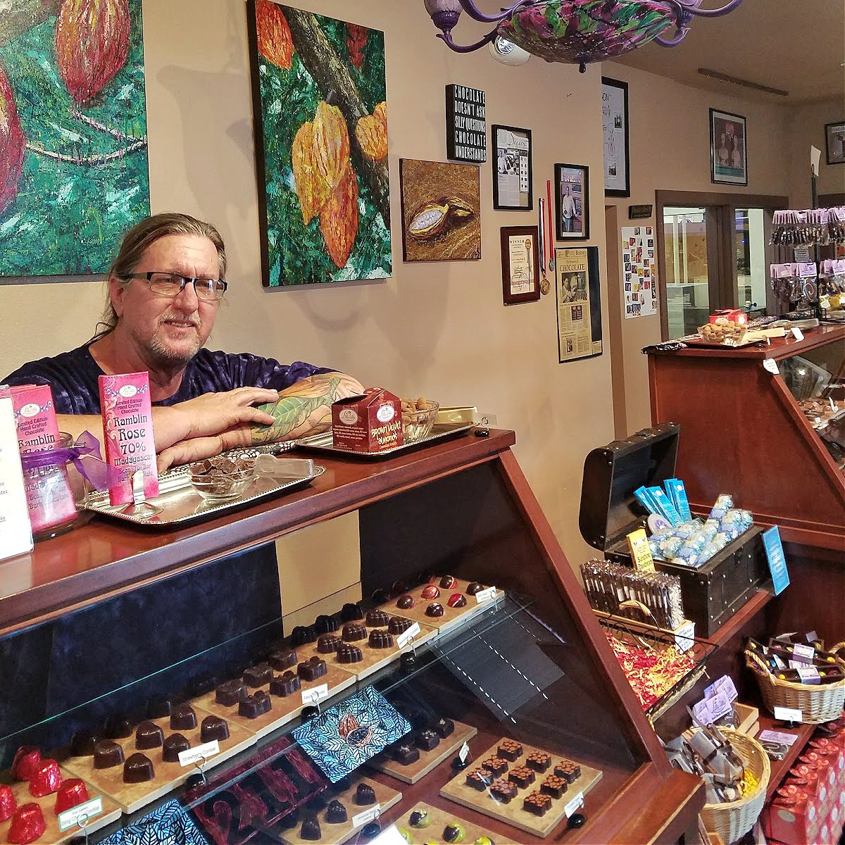 Interior of Lillie Belle Farms shop. Jeff standing behind a glass counter filled with various chocolates.