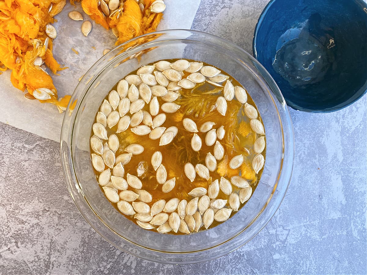 Pumpkin seeds floating in a bowl of water. 