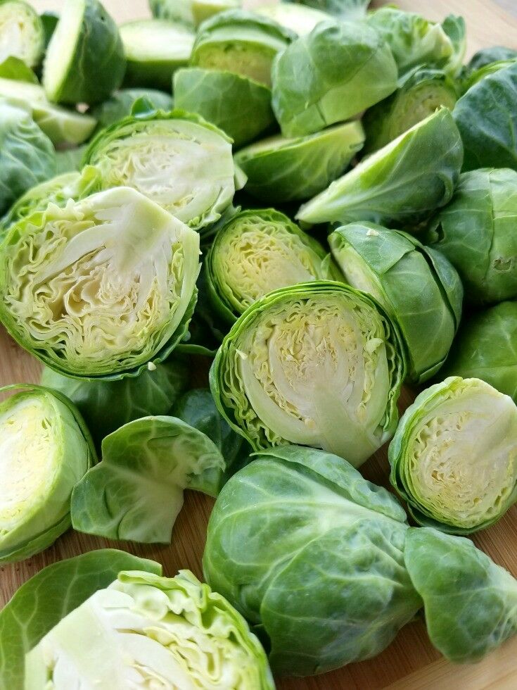 Raw Brussels sprouts cut in half, on a cutting board.