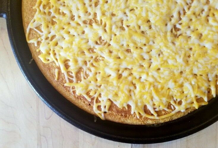 Baked cornmeal round "polenta" crust on cast iron griddle with grated cheese melted on top. 