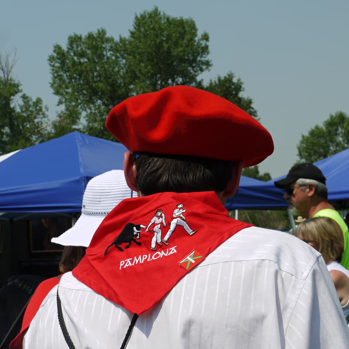 Basque man from behind, wearing red embroidered scarf and red Basque beret. 