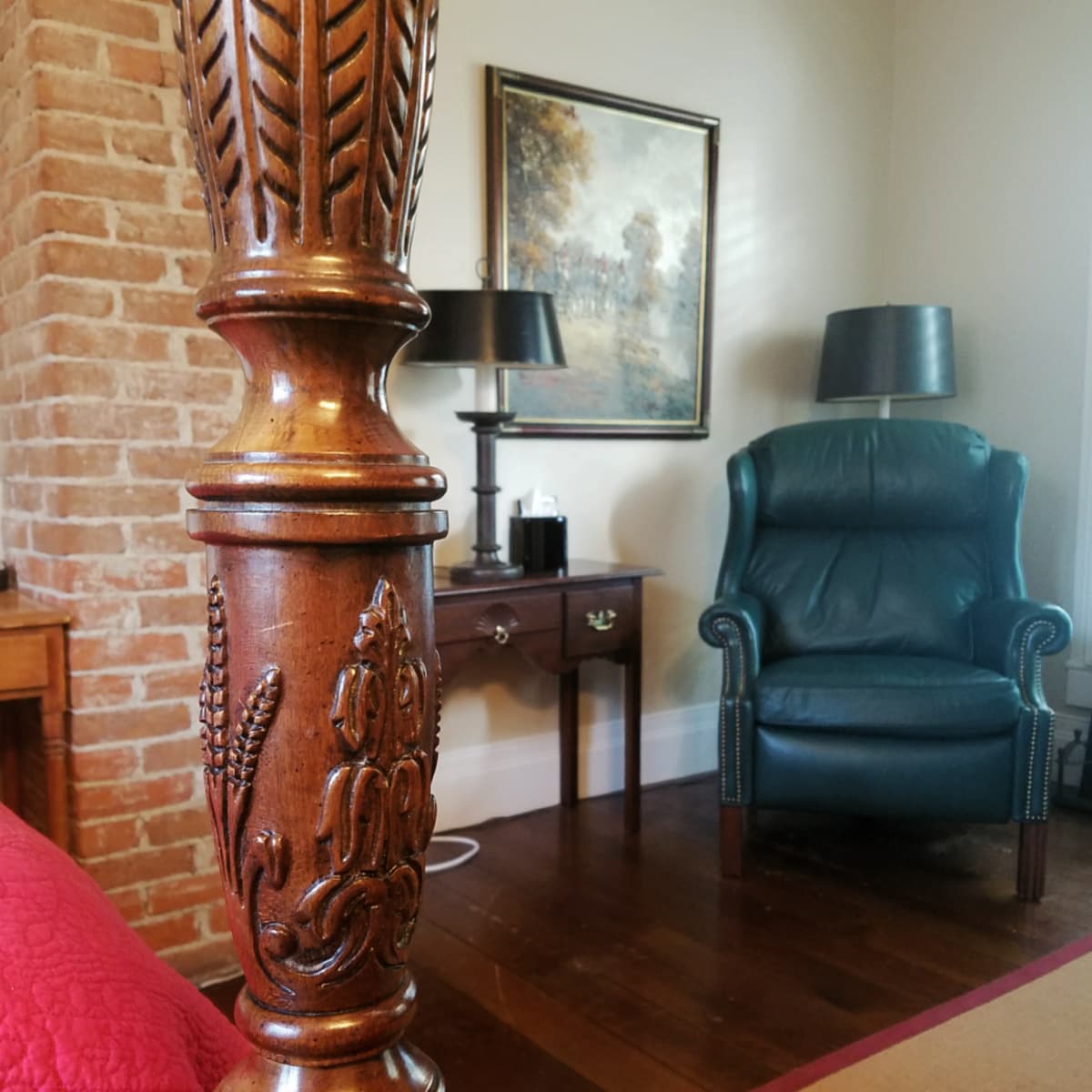 Interior of bedroom in McCully House. Carved bedpost in foreground. 