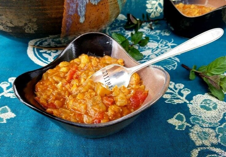 Stew in a small bowl, with a spoon engraved with "Lentils" sticking out the middle. 