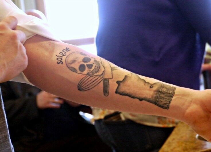 One of Chef Andrew's "chef tattoos": Skull with knife & whisk in place of crossed-bones. "Soigné" above skull.