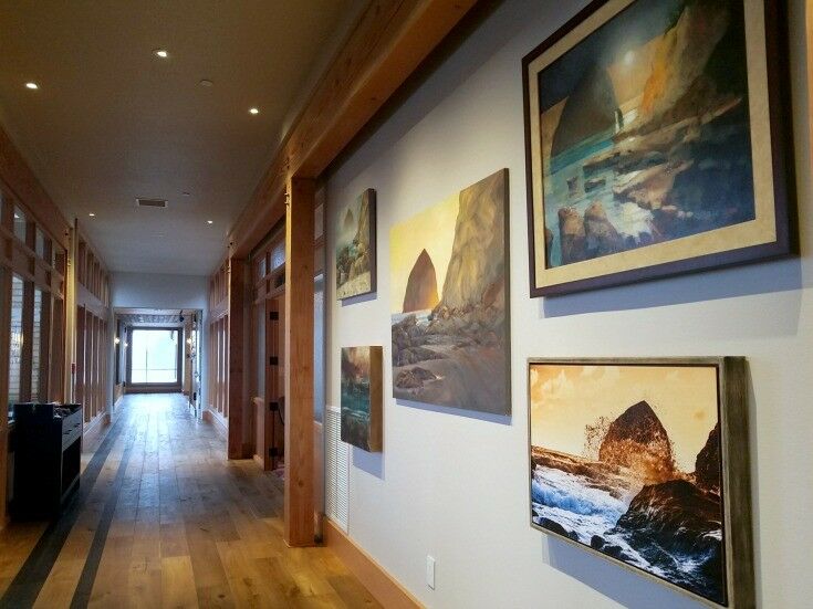 Looking down long hallway lined with wood beams and paintings of coastal scenes. 