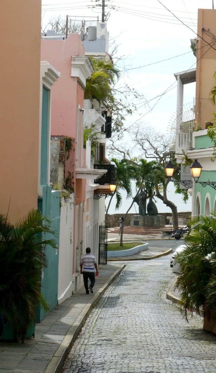 Man walking down a street lined with colorful apartment houses. 