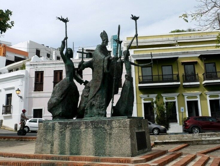 Statue of a bishop and three women carrying torches in a religious procession