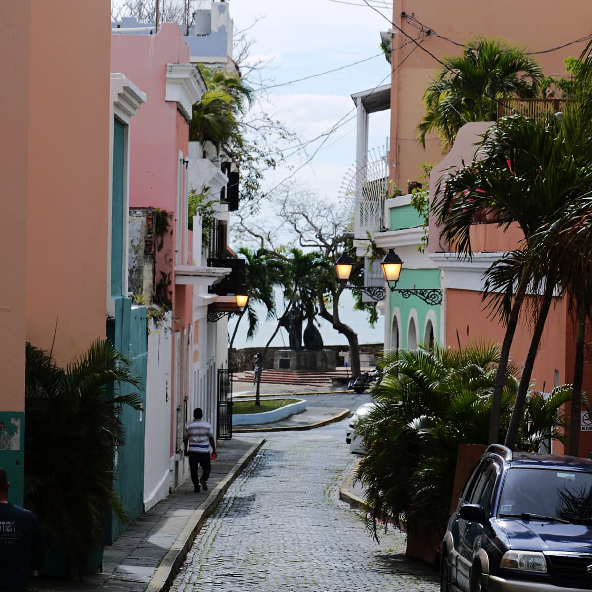Man walking down a street lined with colorful apartment homes in Old San Juan. 