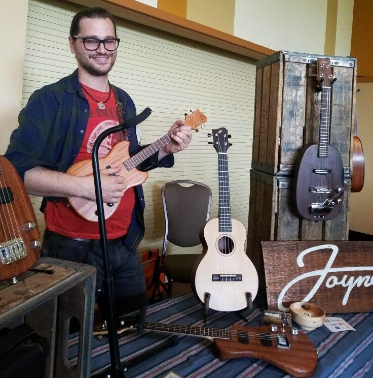 Adam Mendel holding one of his beautiful wood electric ukuleles. 