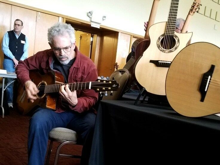 Older man playing an acoustic-electric guitar. 