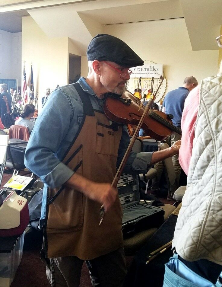 Man in a cap playing a viola. 