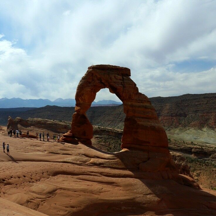 Delicate Arch in all its glory. Sun shining, clouds in the background. 