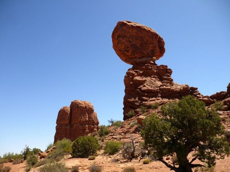 A large, egg-shaped rock balancing on top of a smaller sandstone "stand."